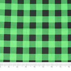 a green and black checkered fabric with a ruler in front of the plaid pattern