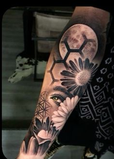 a man's arm with flowers and a half - moon tattoo on the forearm