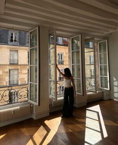 a woman standing in an empty room looking out the window