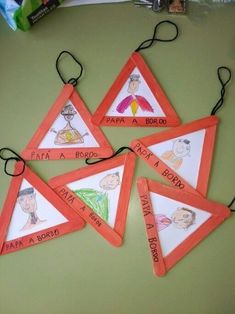 four orange and white triangle shaped tags with children's drawings on them sitting on a table