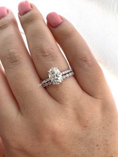 a woman's hand with two engagement rings on top of her finger and the other ring