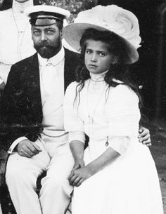 an old black and white photo of a man and woman sitting next to each other