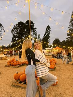 two women hugging each other in front of pumpkins