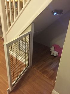 a dog gate in the corner of a room next to a stair case with a stuffed animal on it