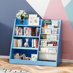 a blue book shelf with books and toys on it in front of a colorful wall