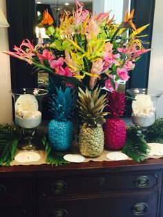 pineapples, flowers and candles on a dresser in a room with a mirror