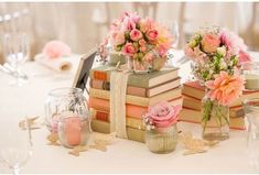 there are many books on the table with flowers in vases and glasses next to each other