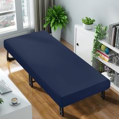 a large blue mattress sitting on top of a hard wood floor next to a computer desk