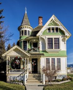 an old victorian style house with green trimmings and a wreath on the front porch