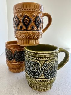 three coffee mugs sitting next to each other on top of a white countertop