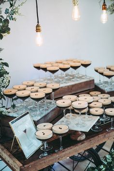 a table topped with lots of wine glasses filled with desserts and pies on top of wooden trays