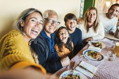 a group of people sitting at a table with food and drinks in front of them