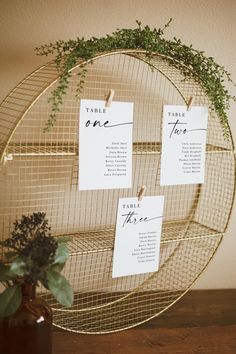 there are three place cards on a wire rack with a plant in the middle and two tags attached to it