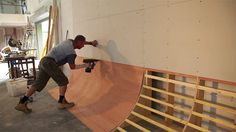 a man is skateboarding on a ramp in a room with wood floors and walls