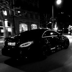 a black car driving down the street at night