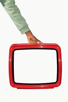 a person holding a red and black television set in front of a white background with one hand on top of the tv