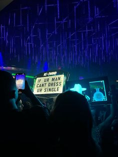 a group of people holding up cell phones in front of a sign that reads if our man can hear us single