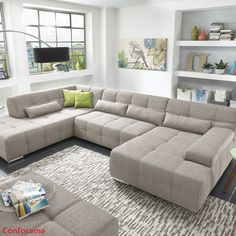 a living room with a large sectional couch and coffee table in front of the window