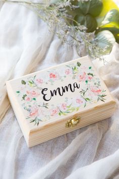 a small wooden box with the word mmmm on it sitting next to some flowers