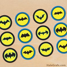 the batman cupcake toppers are yellow and blue with black bat logos on them