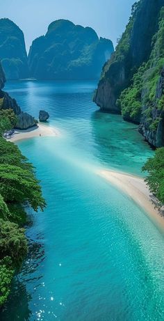 an aerial view of the water and beach in front of some mountains with green trees