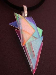 a multicolored glass origami pendant on a black cord