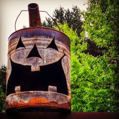 an old rusted metal barrel with a jack - o'- lantern face painted on it