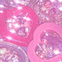 there are many heart shaped objects on the table with pink glitters and pearls in them