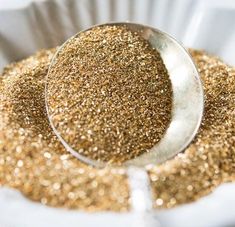 a spoon full of gold glitter sitting on top of a paper plate