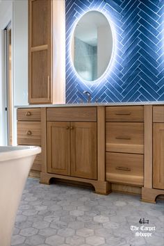 a bathroom with blue tile and wooden cabinets in the corner, along with a white bathtub