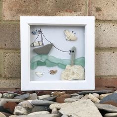 a white frame with some rocks and a boat in it