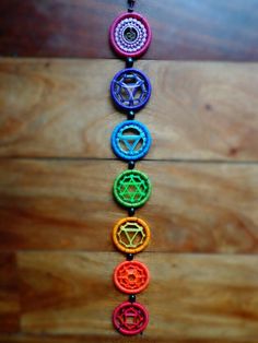 the seven chakras are arranged in a row on a wooden surface with beads hanging from them