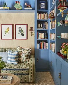 a living room filled with furniture and bookshelves covered in blue paint on the walls