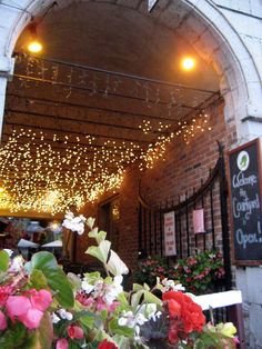 the entrance to a restaurant with flowers and lights