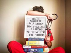 a person sitting on the floor holding a stack of books with a pair of scissors in front of them