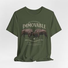 the t - shirt is green and has two pigs on it, with words that say immovable