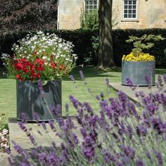 two large metal planters with flowers in them