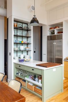 a kitchen with wooden floors and white walls, open shelves on the wall above the island