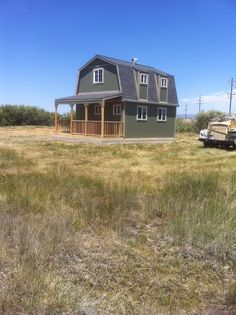 a truck is parked in front of a house on the side of a field with grass