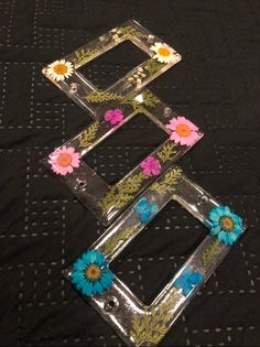 three metal frames with flowers on them sitting on a black cloth covered tablecloth,