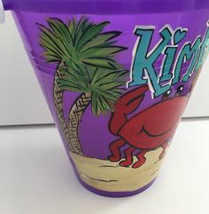 a purple bucket with a crab and palm tree on it