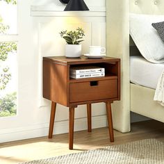 a bedside table with a book on it next to a lamp and bed in a bedroom