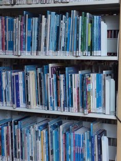 a book shelf filled with lots of books on top of white shelving unit shelves