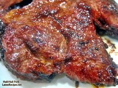 some meat is sitting on a white plate with brown stuff all over it's surface