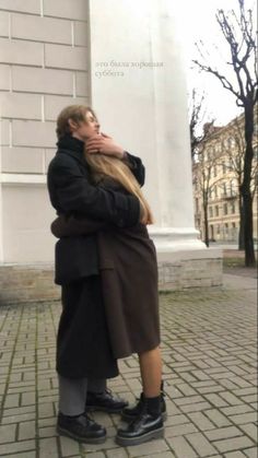 a man and woman hugging in front of a monument