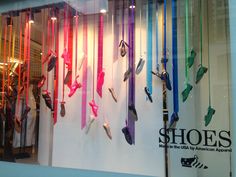 there are many pairs of shoes on display in the store window with ribbons hanging from them