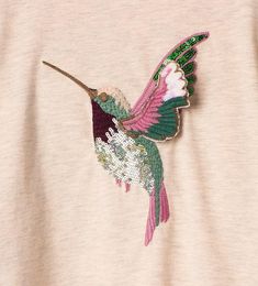 a pink and green hummingbird embroidered onto a t - shirt with sequins