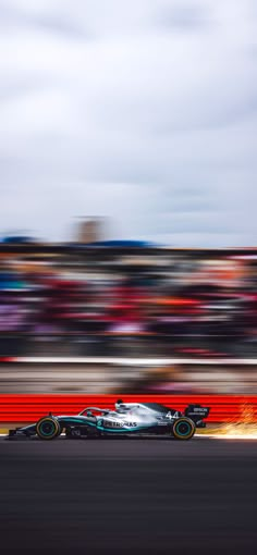 a race car driving down the track in front of a large group of people watching