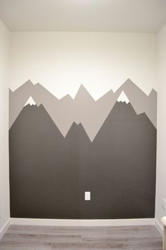 an empty room with mountains painted on the wall and wood flooring in front of it