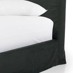 a bed with two white pillows on top of it and a black headboard in the middle